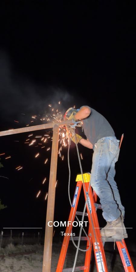 Luke welding at night on a ladder, sparks flying, Comfort Texas